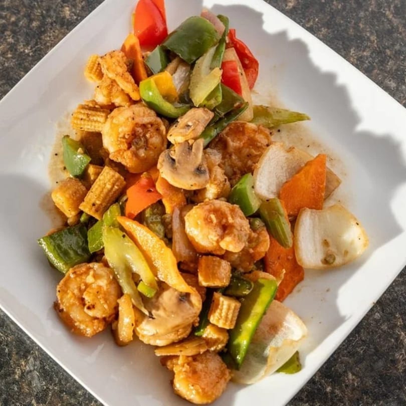 New Hong Kong House's shrimp stir-fry with colorful vegetables, mushrooms, and baby corn on a white plate.
