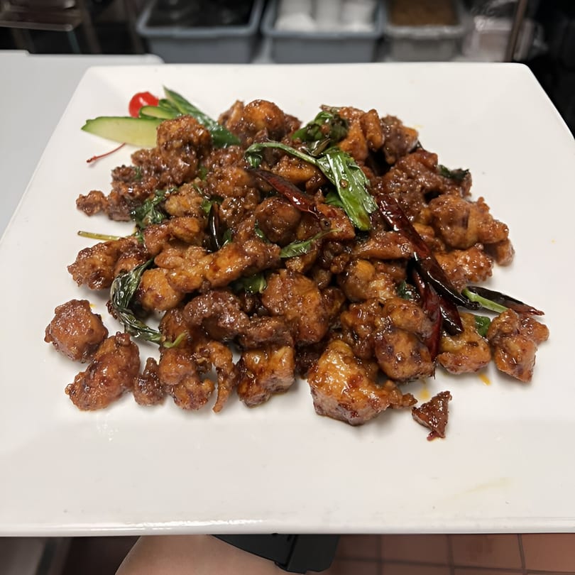 New Hong Kong House's General Tso's chicken, garnished with green onions, dried chilies, and cucumber slices.